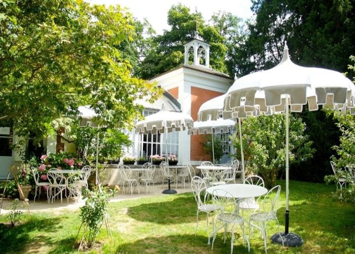 Terrasse jardin du salon de thé Les Thés Brillants à Châtenay-Malabry, avec parasols et tables blanches
