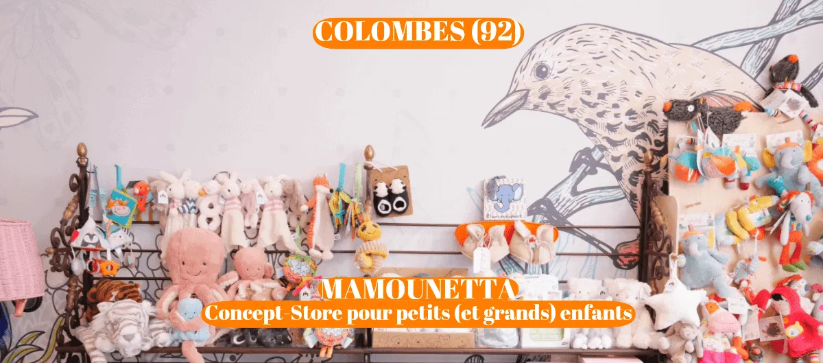 Étagère d'une boutique pour enfants garnie de peluches colorées devant un mur illustré d'un oiseau