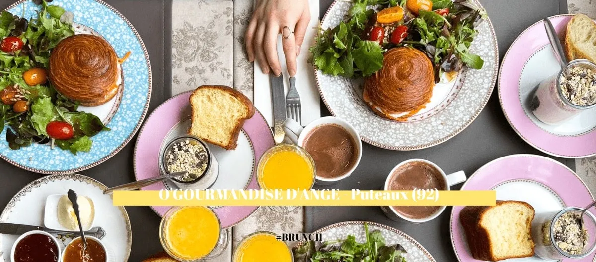 Table de brunch vue de dessus avec salades, viennoiseries, chocolats chauds et jus d'orange.