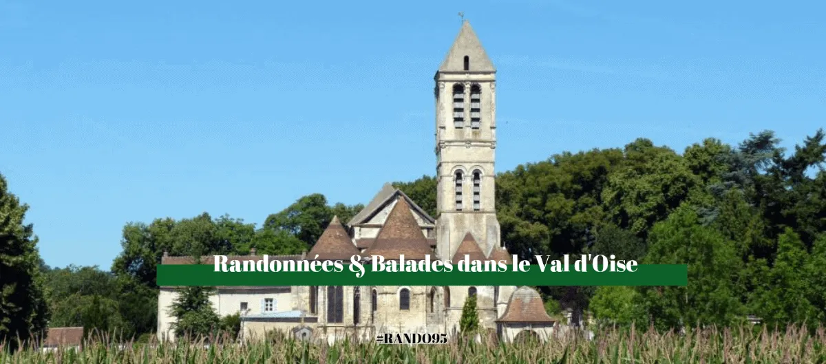 Église en pierre au haut clocher, entourée d'arbres et de champs, dans le Val-d'Oise.