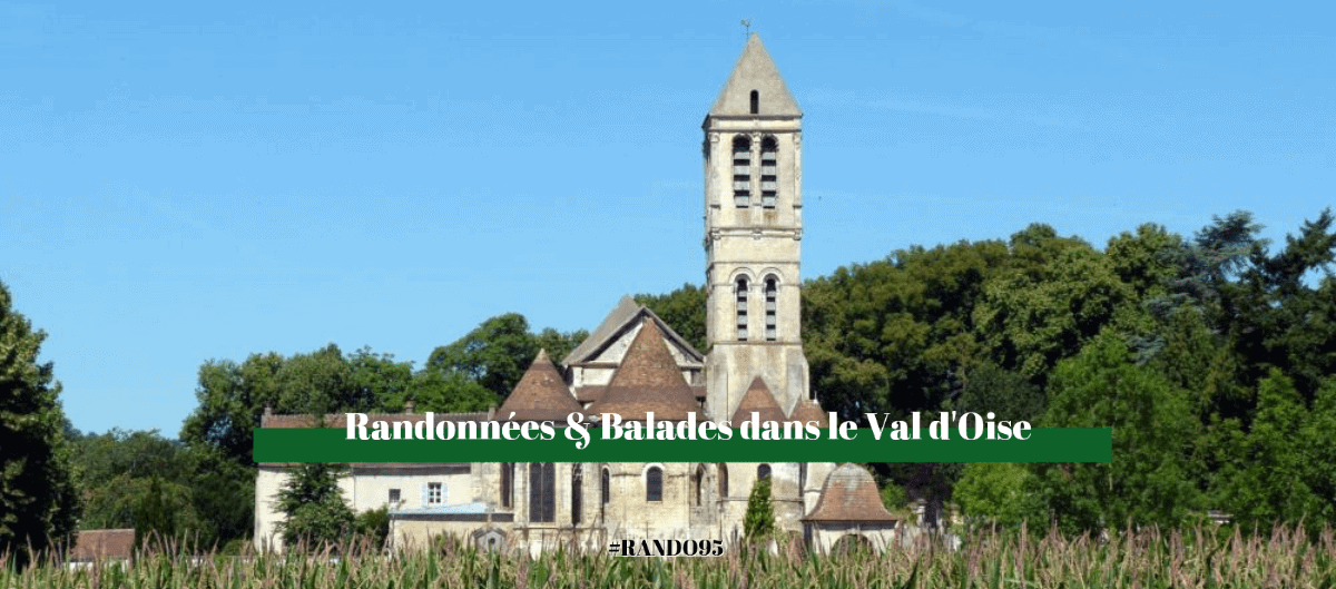 Église en pierre au haut clocher, entourée d'arbres et de champs, dans le Val-d'Oise.