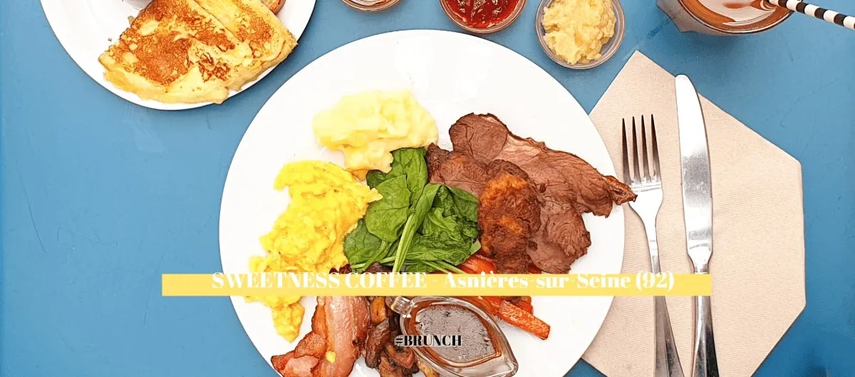 Assiette de brunch garnie d'œufs brouillés, pain perdu, viande rôtie et épinards sur une table bleue