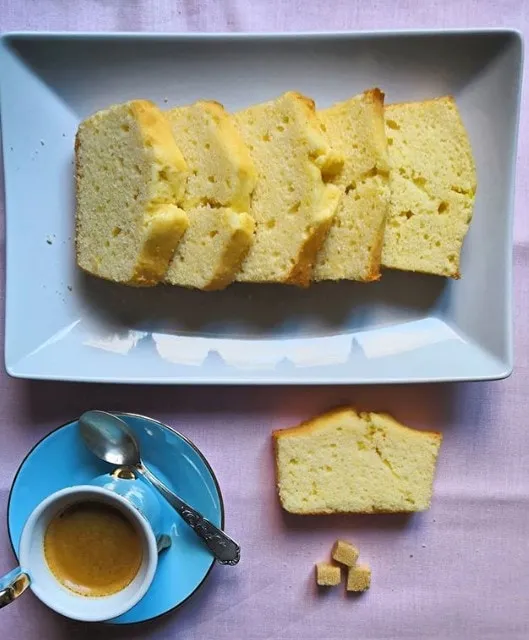 Cake tranché sur un plat bleu, servi avec un café expresso et des morceaux de sucre.