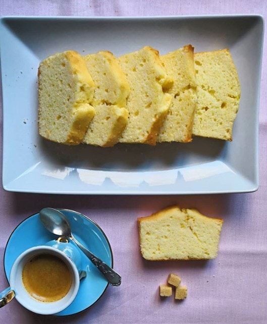 Cake tranché sur un plat bleu, servi avec un café expresso et des morceaux de sucre.