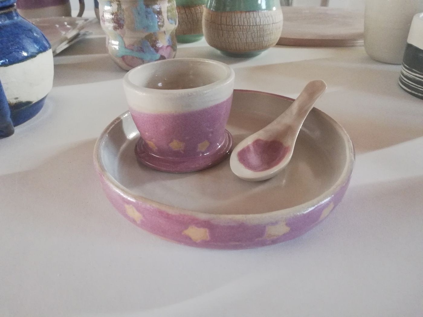 Tasse et soucoupe en céramique artisanale rose décorées d'étoiles, avec une petite cuillère assortie