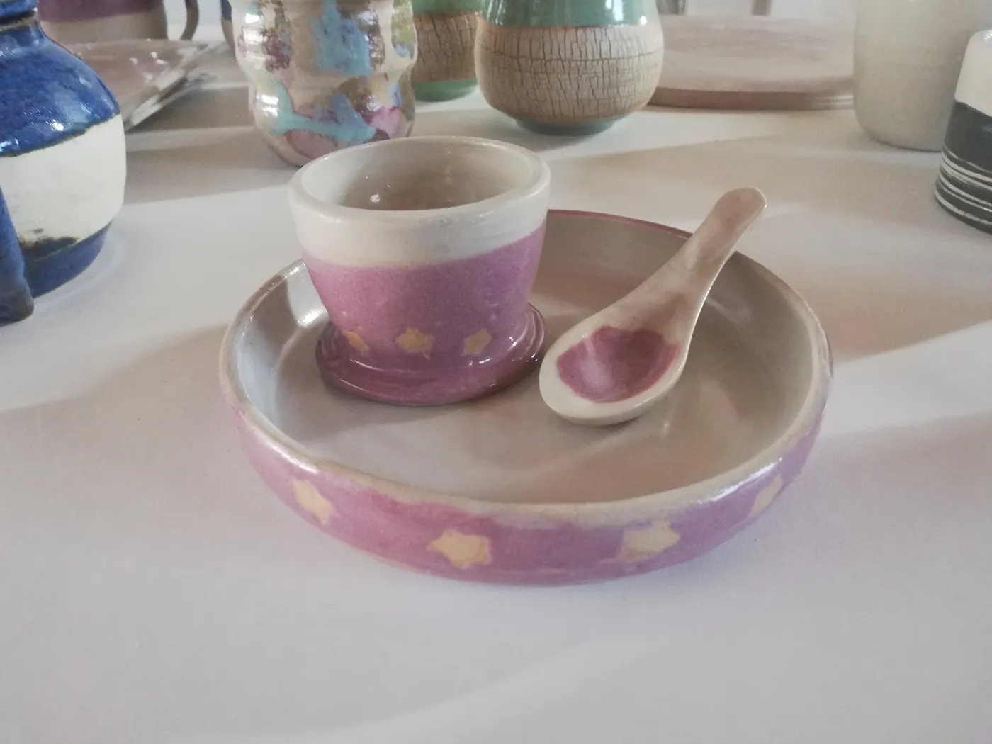 Tasse et soucoupe en céramique artisanale rose décorées d'étoiles, avec une petite cuillère assortie