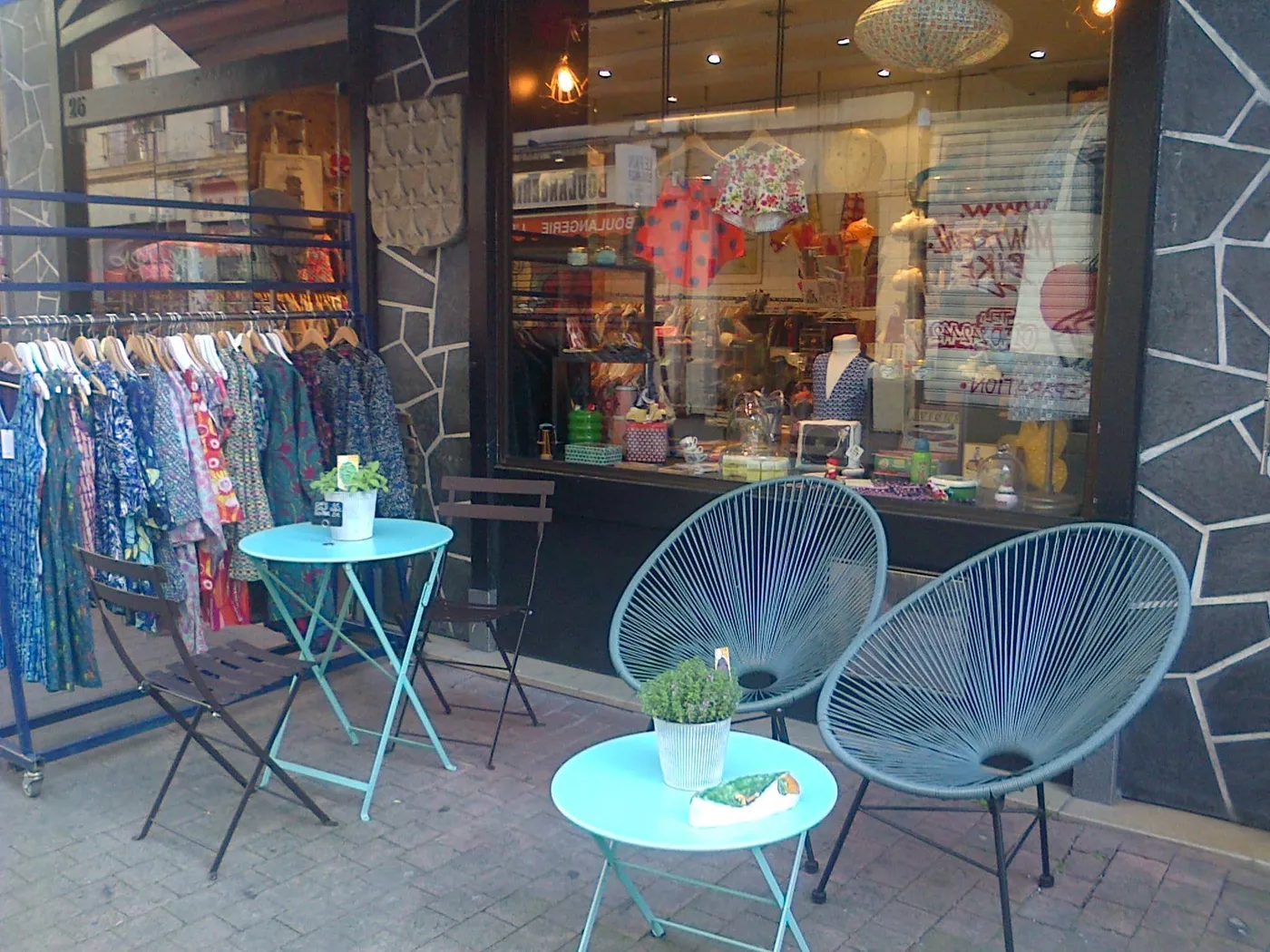 Devanture de la boutique Saperlipopette à Montreuil avec portants de vêtements et fauteuils sur le trottoir