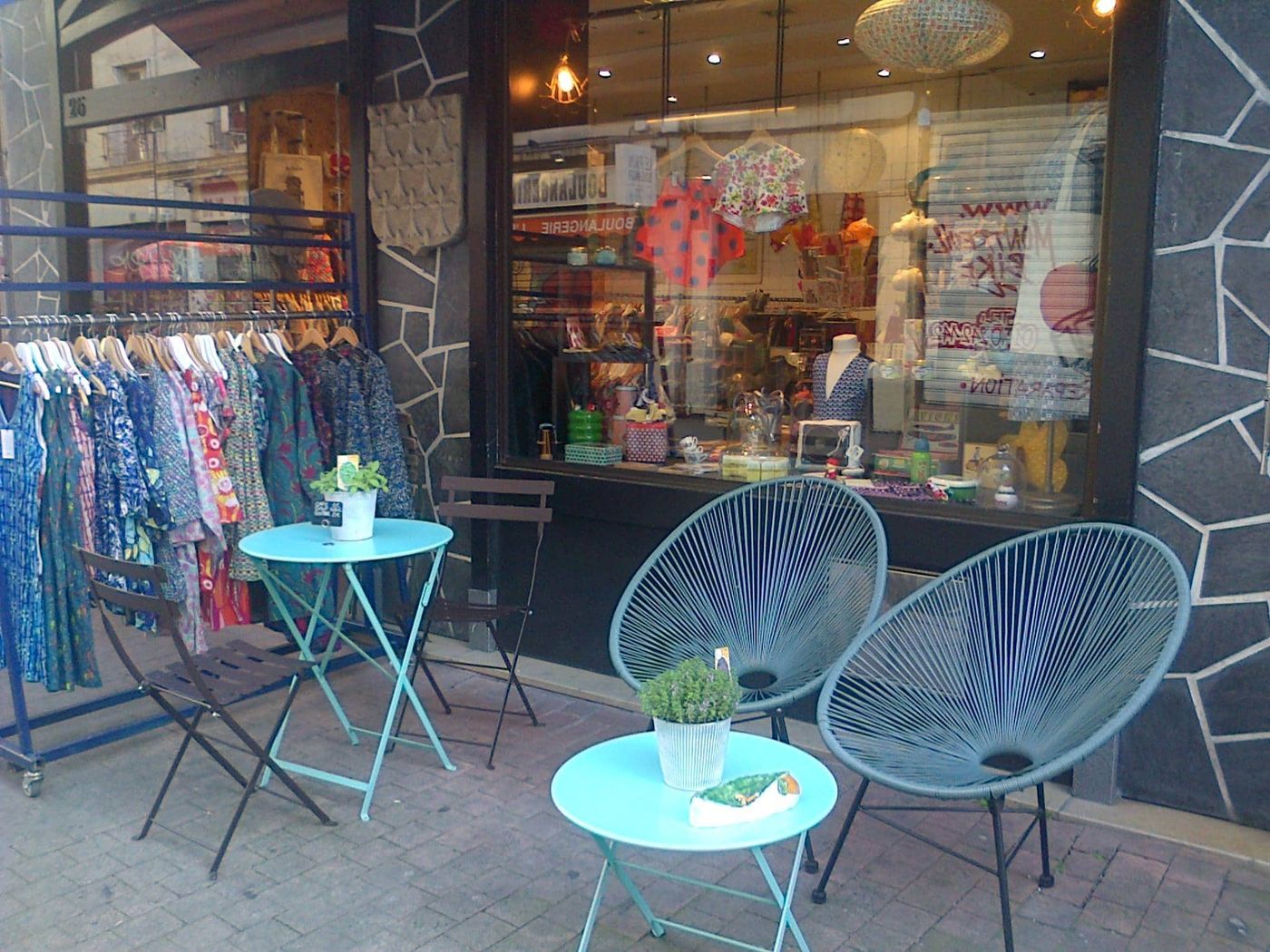 Devanture de la boutique Saperlipopette à Montreuil avec portants de vêtements et fauteuils sur le trottoir