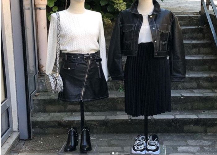 Deux mannequins habillés de tenues en cuir noir devant la vitrine d'une boutique