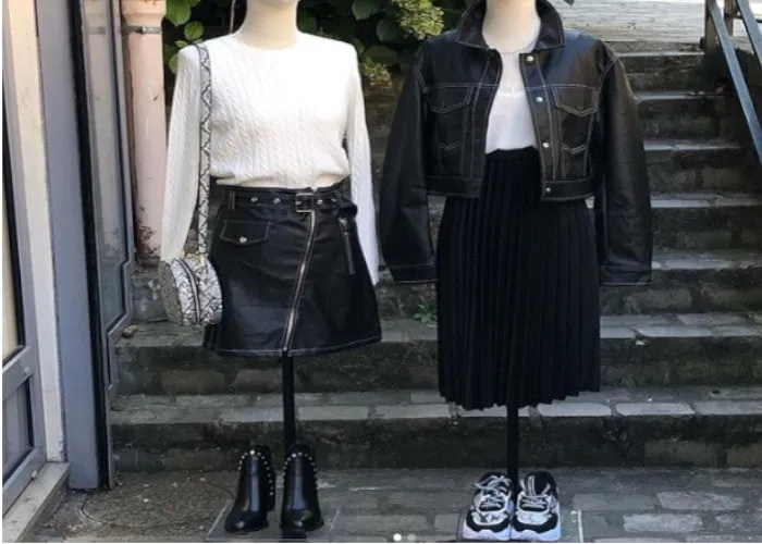 Deux mannequins habillés de tenues en cuir noir devant la vitrine d'une boutique